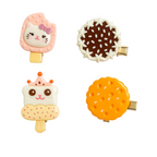 Four colorful hair clips shaped like ice cream cones and cookies on a white background