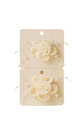 Pair of white floral earrings on clear cards with a beige background