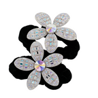Two black hair ties with silver flower-shaped ends featuring multicolored stones on a white background.