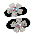 Two black hair scrunchies with silver flower-shaped embellishments on a white background