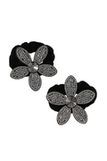 Black flower-shaped earrings with diamond-like stones on a white background