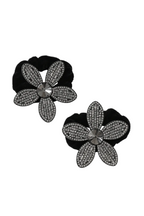 Black flower-shaped earrings with diamond-like stones on a white background