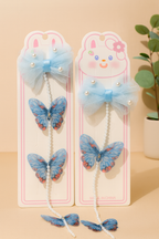Two blue butterfly hair accessories on pink cards with a beige background