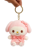 Pink plush keychain with a bow held by a hand on a white background
