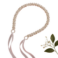Pearl belt with ribbons on a pink background with flowers