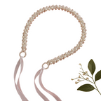 Pearl belt with ribbons on a pink background with flowers