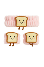 Three plush toys shaped like slices of bread with smiling faces on a white background