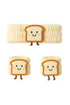 Three cute bread-shaped cookies with smiling faces on a white background