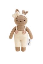 Crocheted deer toy with a white bib and flowers on a light background