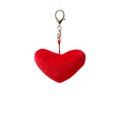 Red heart-shaped keychain on a neutral background with plants
