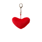 Red heart-shaped keychain on a neutral background with plants
