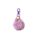 Purple fluffy keychain with a face on a beige surface with plants in the background
